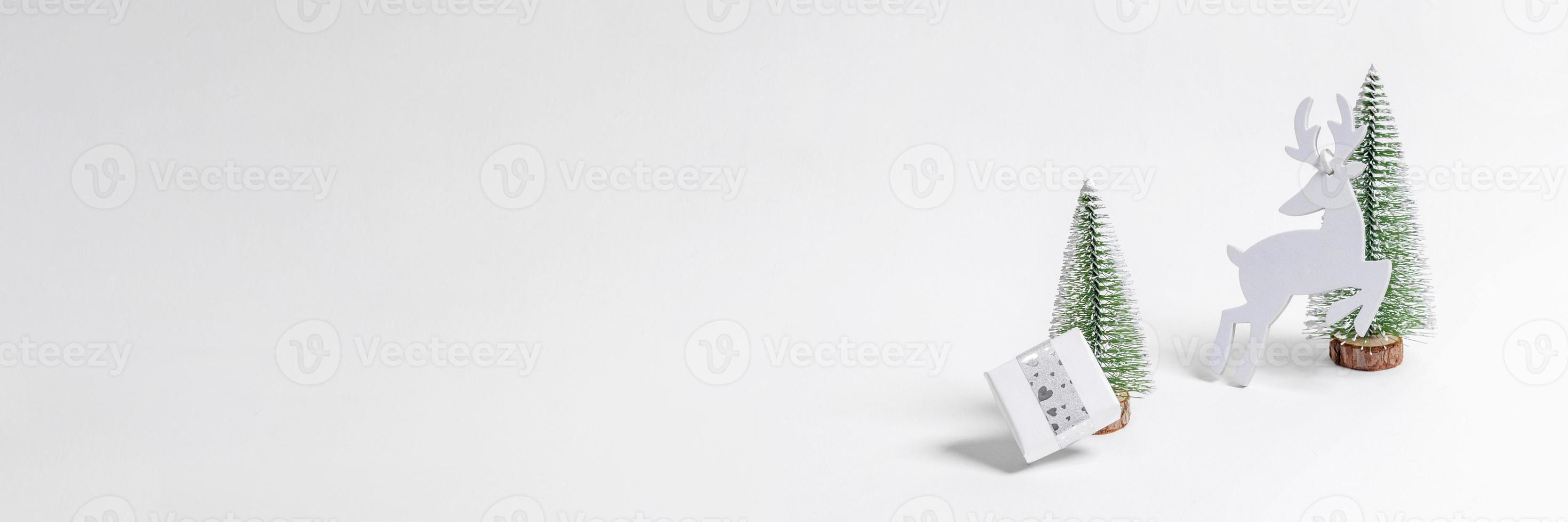 Christmas festive wide white minimal banner. Christmas decorations Xmas trees, DIY gift box and deer on white. photo