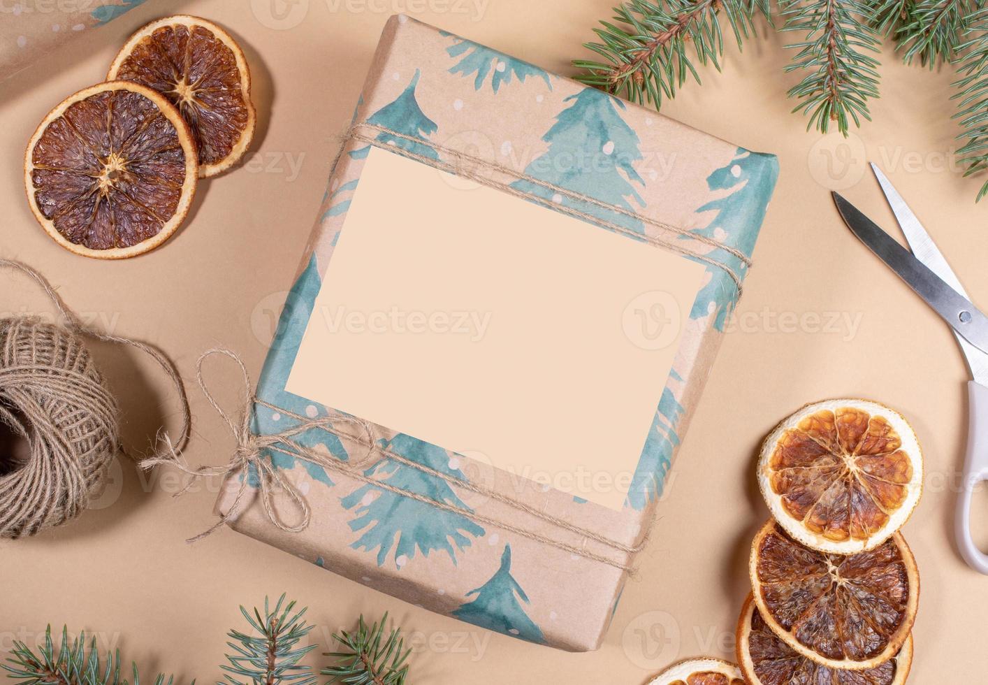 Christmas or New Year DIY wrapped in festive paper gift box with empty space on beige backdrop. photo