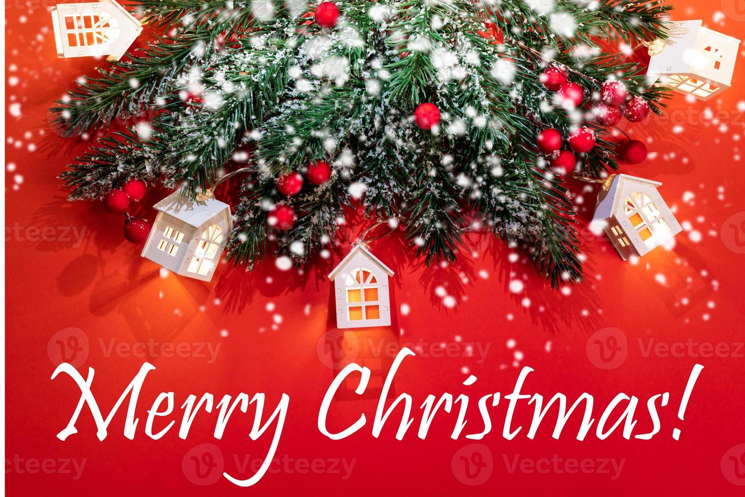 Xmas greeting card with fir branches, Christmas lights white lodges, snow, bokeh on red with caption Merry Christmas. photo