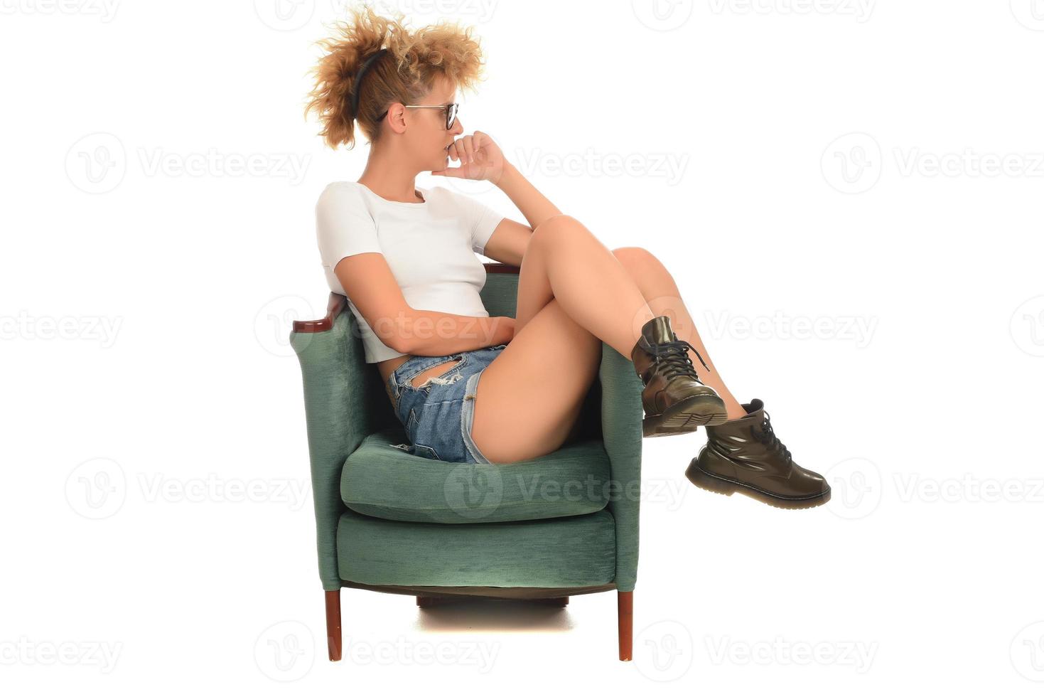 mujer rubia loca con estilo de moda sentada en la silla y posando frente a la cámara en el estudio. concepto de belleza de moda. foto
