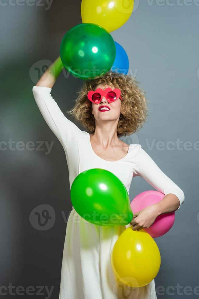 Beautiful Blonde Female Model Holding balloons around her head. Isolated photo