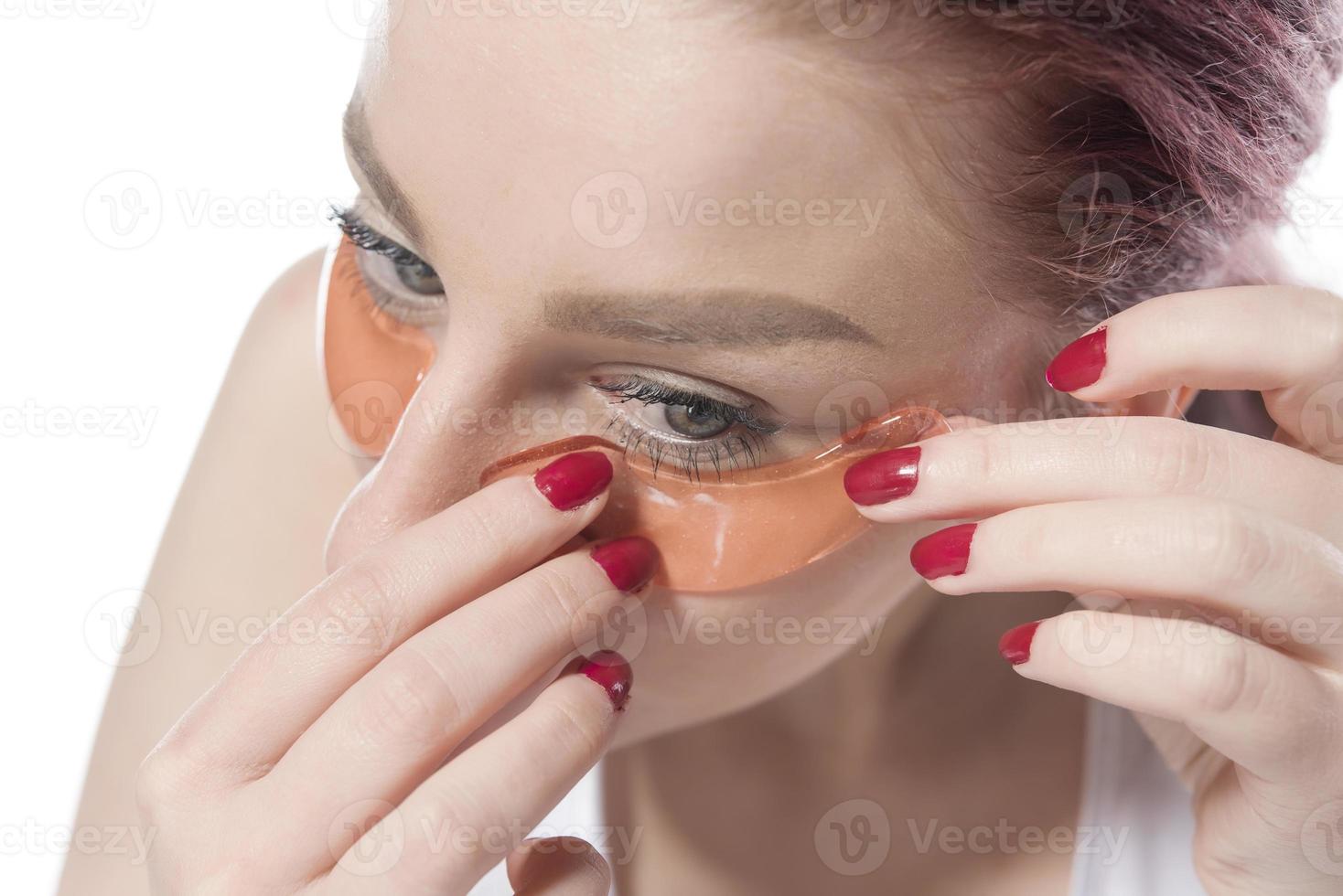 woman with cosmetic patches moisturizing on skin under eyes. photo