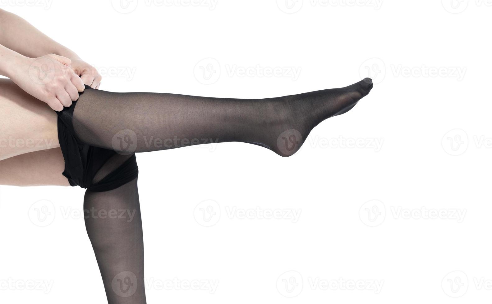 Woman puts on stockings on her beautiful long legs, isolated on white background photo