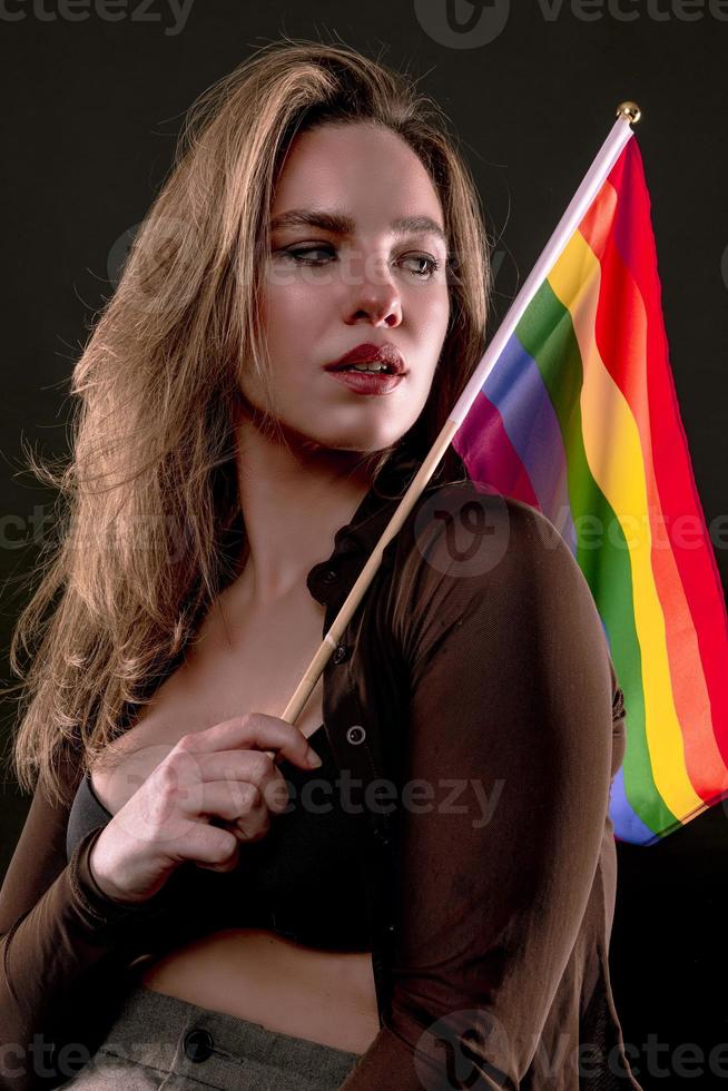 Lesbian woman holding rainbow flag isolated on black background. LGBT International symbol of the lesbian, gay, bisexual and transgender community. photo