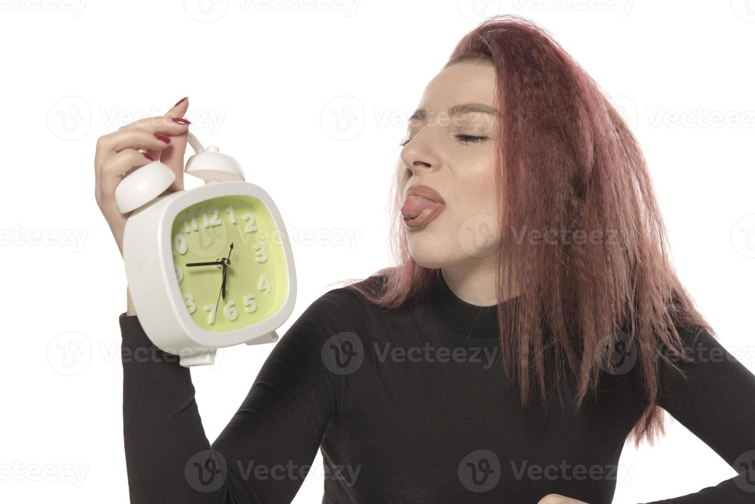 worried young woman holding alarm clock in her hand photo