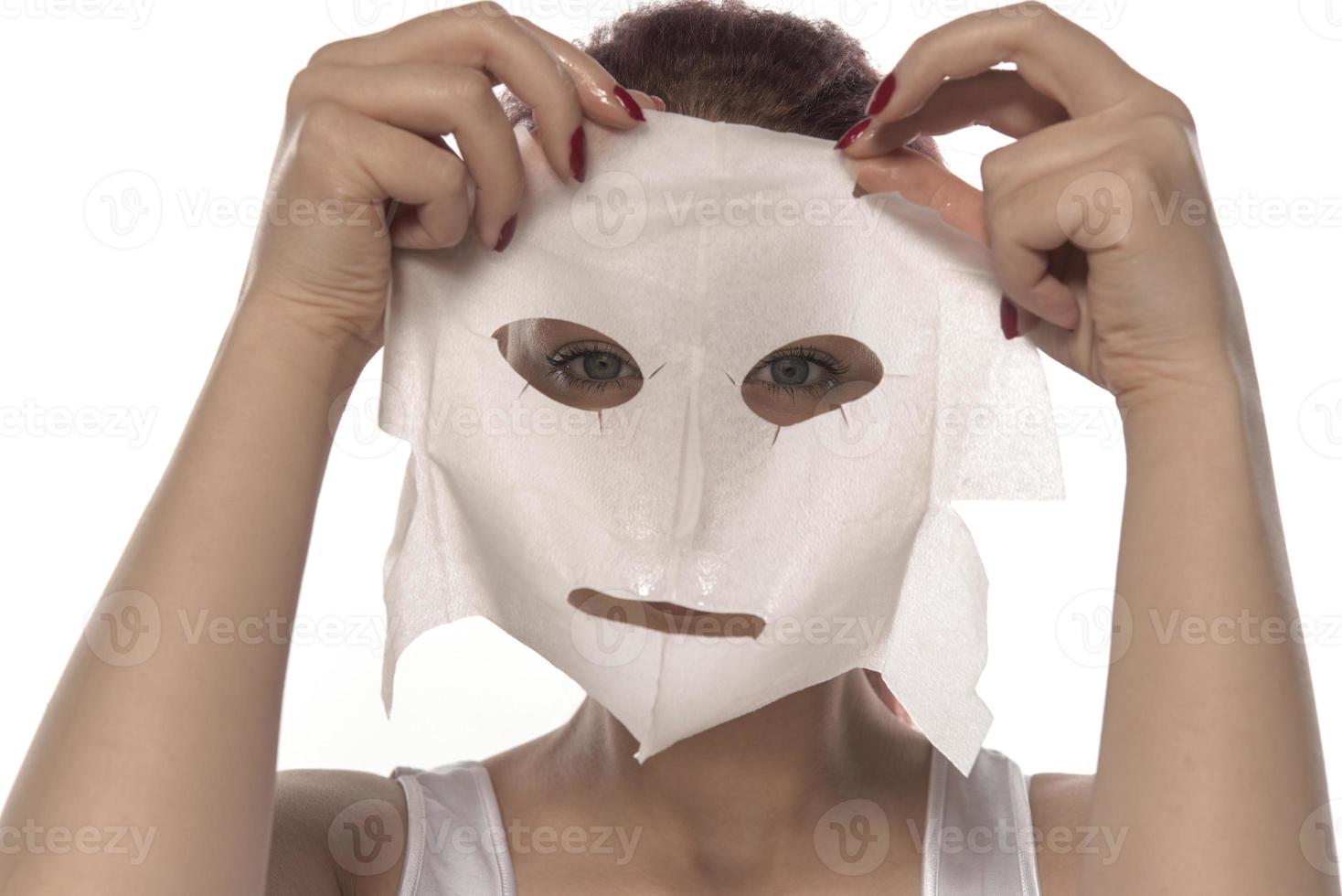 Face care and beauty treatments. Woman with a sheet moisturizing mask on her face isolated on white background photo