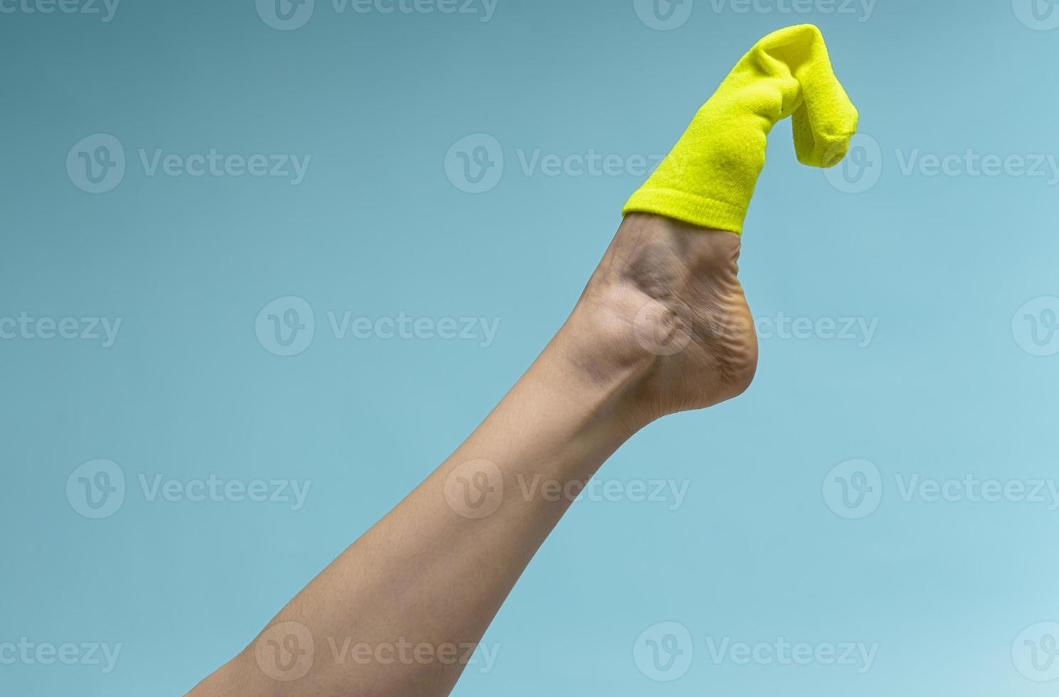 Woman with beautiful legs wears green socks on her feet. Isolated on blue background photo