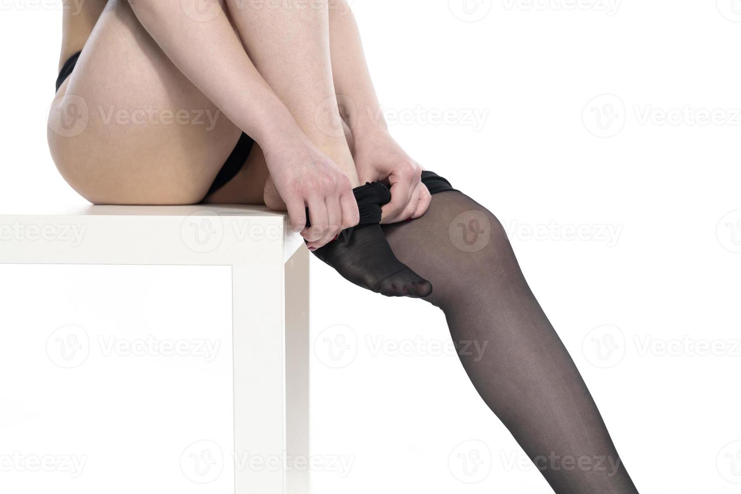 Woman puts on stockings on her beautiful long legs, isolated on white background photo