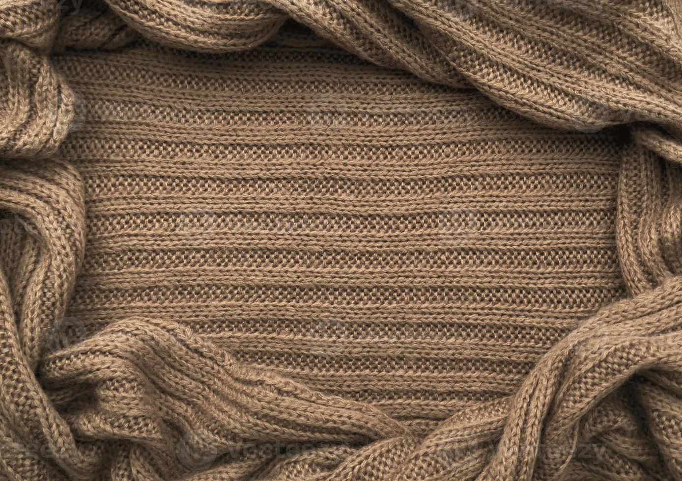 Oval frame for text from brown knitted scarf or sweater texture, top view. Texture background of warm crocheted clothing textile. Knitwear fabric. photo