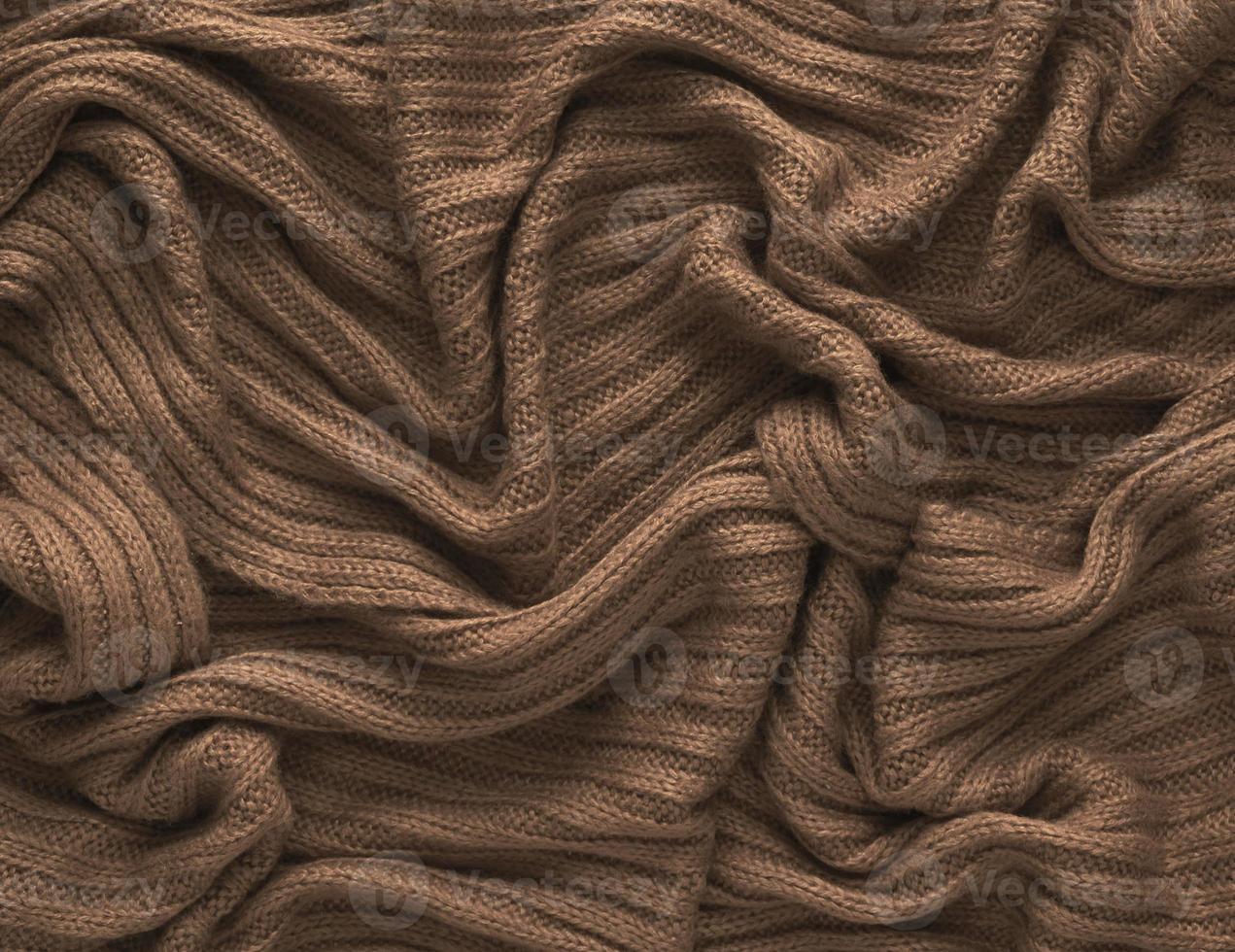 Brown crumpled knitted scarf or sweater texture, top view. Texture background of warm crocheted clothing textile. Knitwear fabric photo