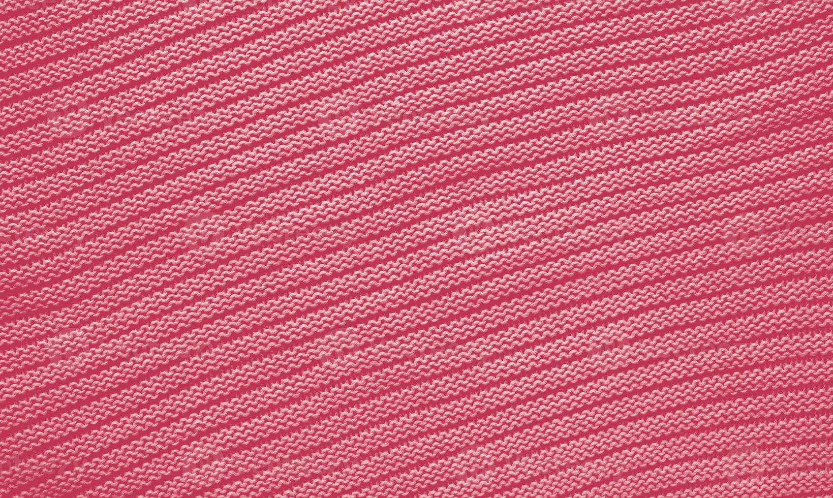 Texture of smooth knitted sweater with pattern. Handmade knitting wool or cotton fabric texture. Background of Large knit pattern with knitting needle or crochet. Color Of The Year 2023 - Viva Magenta photo