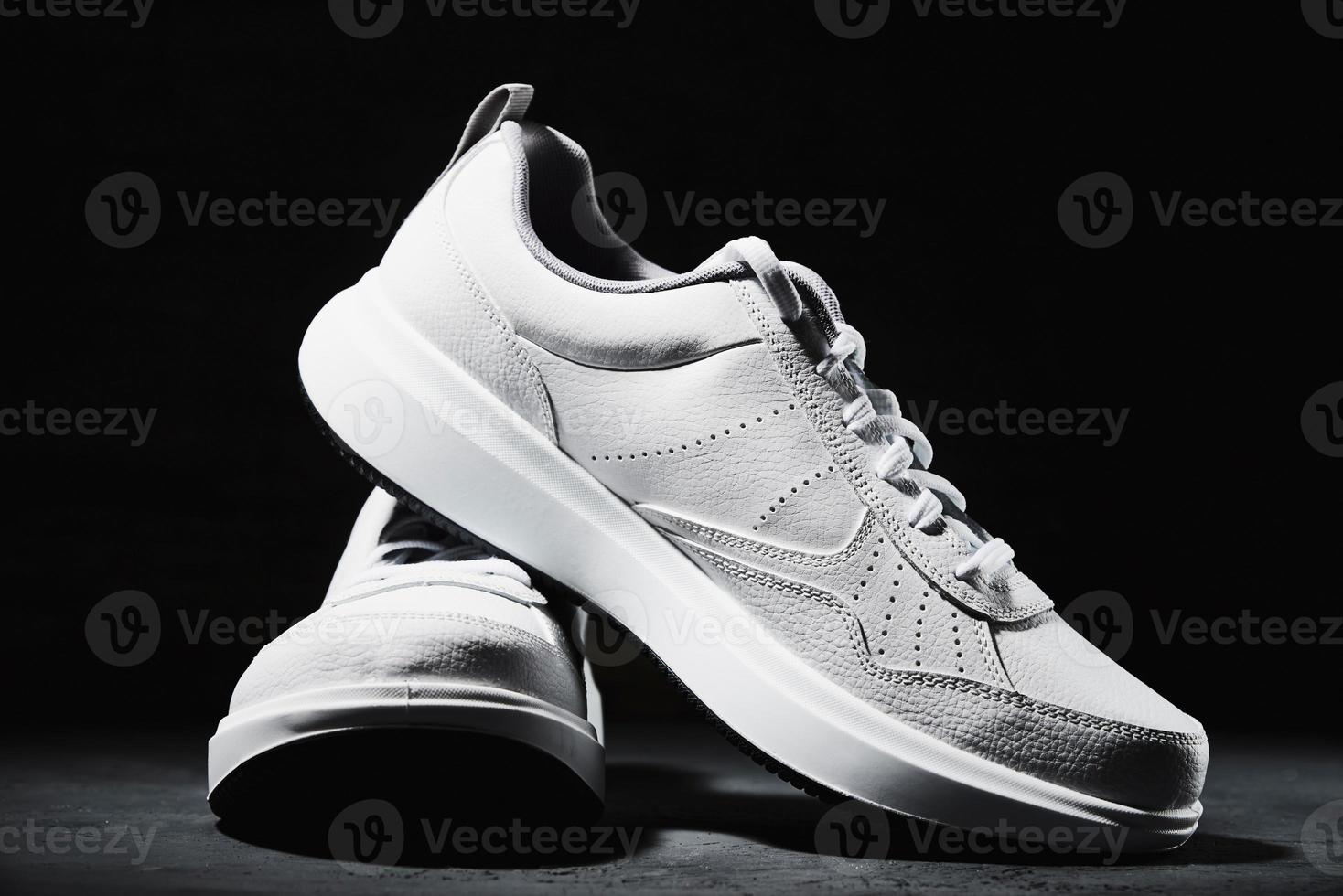 Pair of white sneakers on black background photo