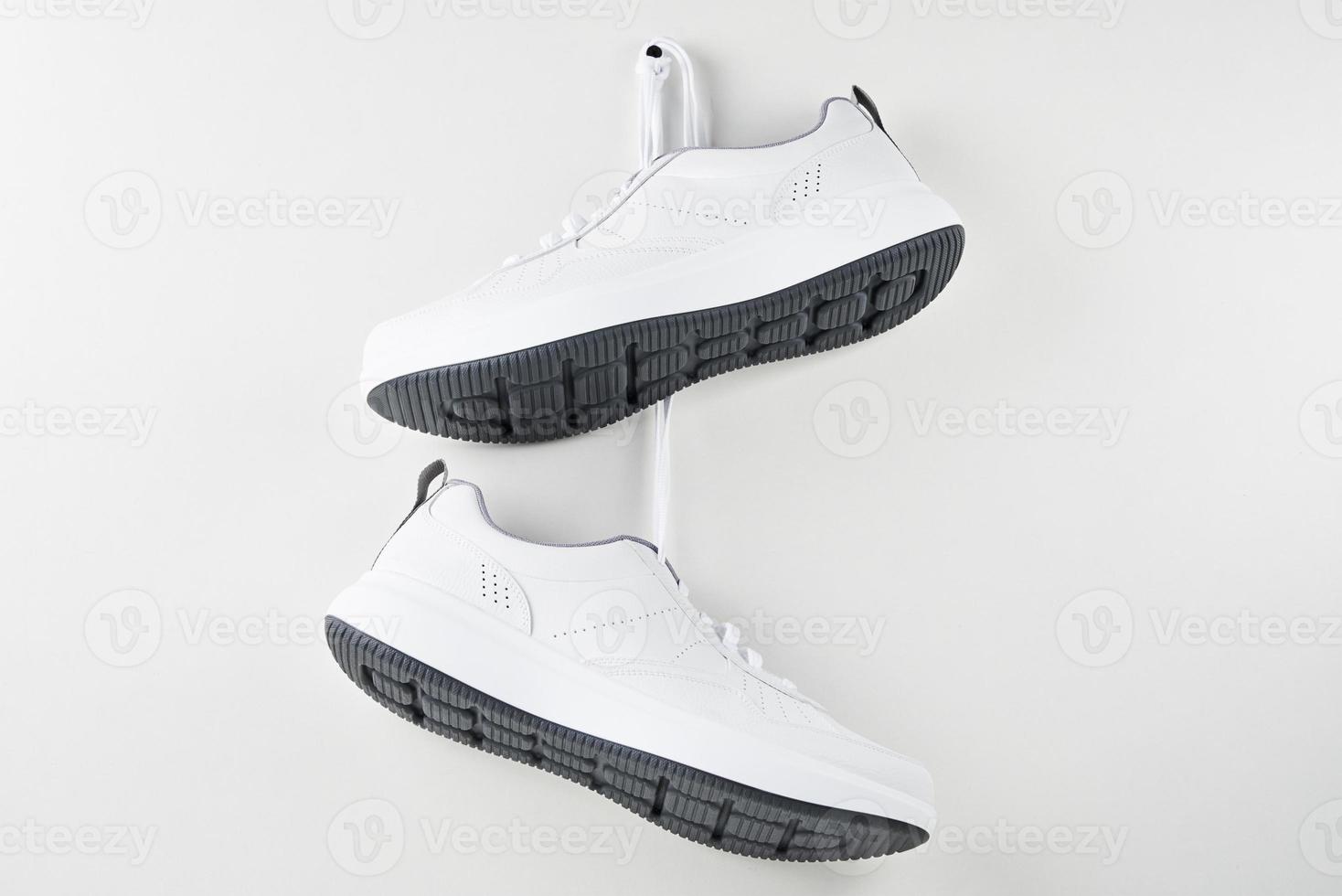 Pair of white male sneakers hanging on wall photo