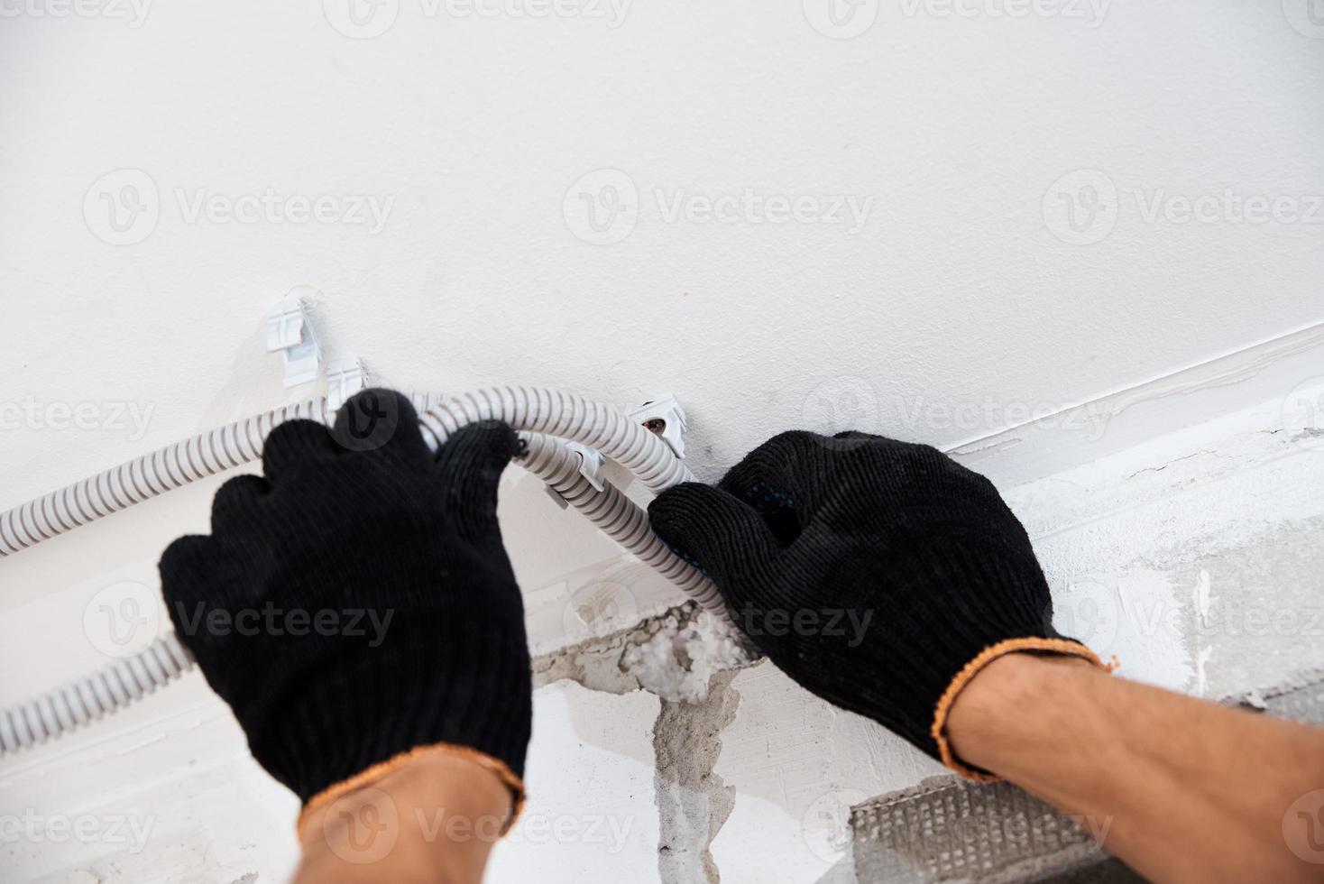 electricista que fija el cable eléctrico a la pared, primer plano foto