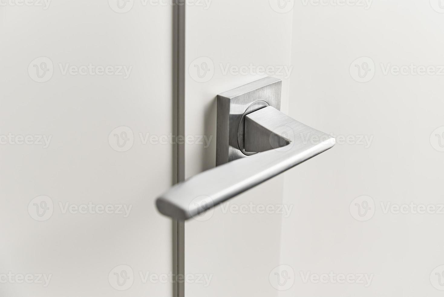 Silver door handle on a white door.  Furniture accesories, interior element photo