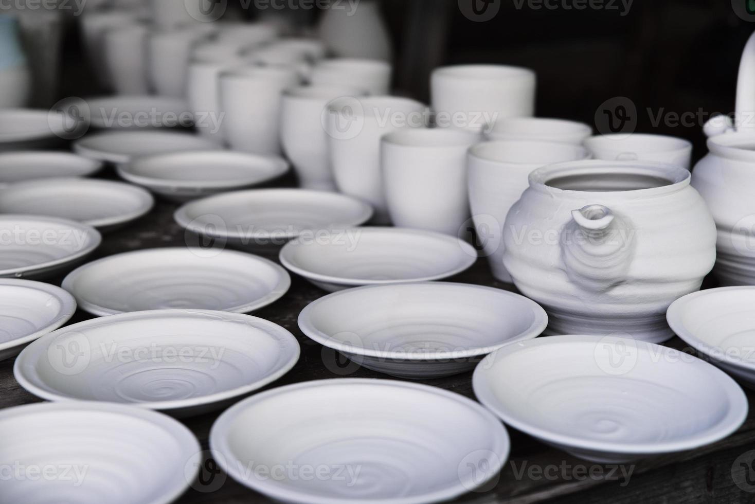 Many handmade clay jugs on shelf in workshop photo