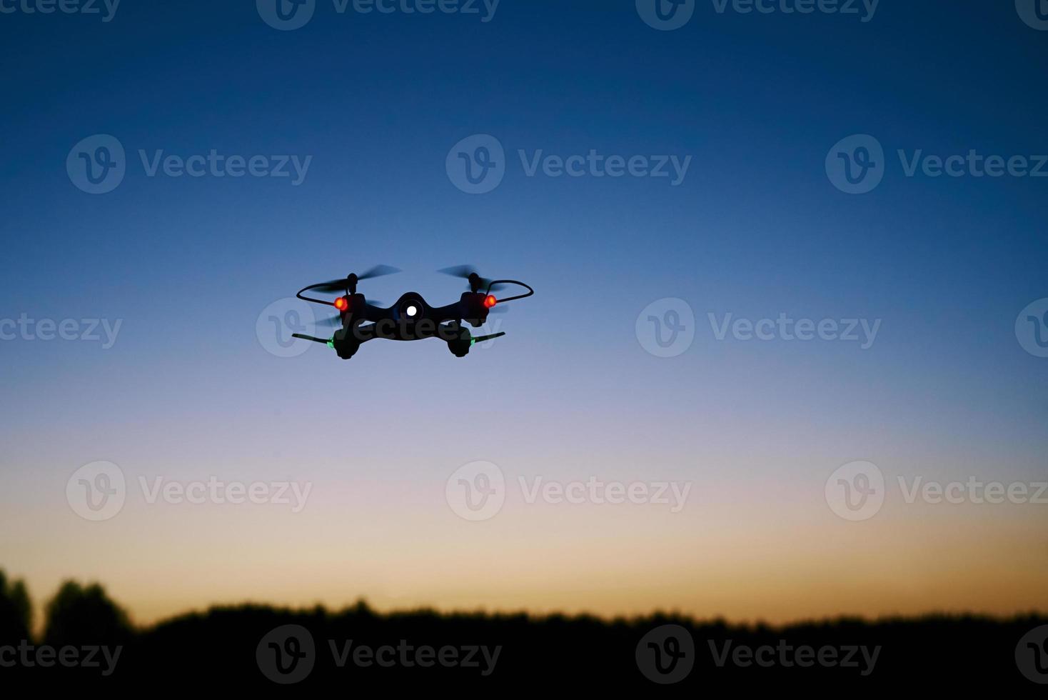 Toy drone quad copter against sunset sky photo