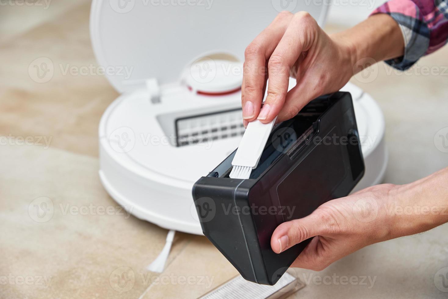 Woman cleans dust container in robotic vacuum cleaner photo