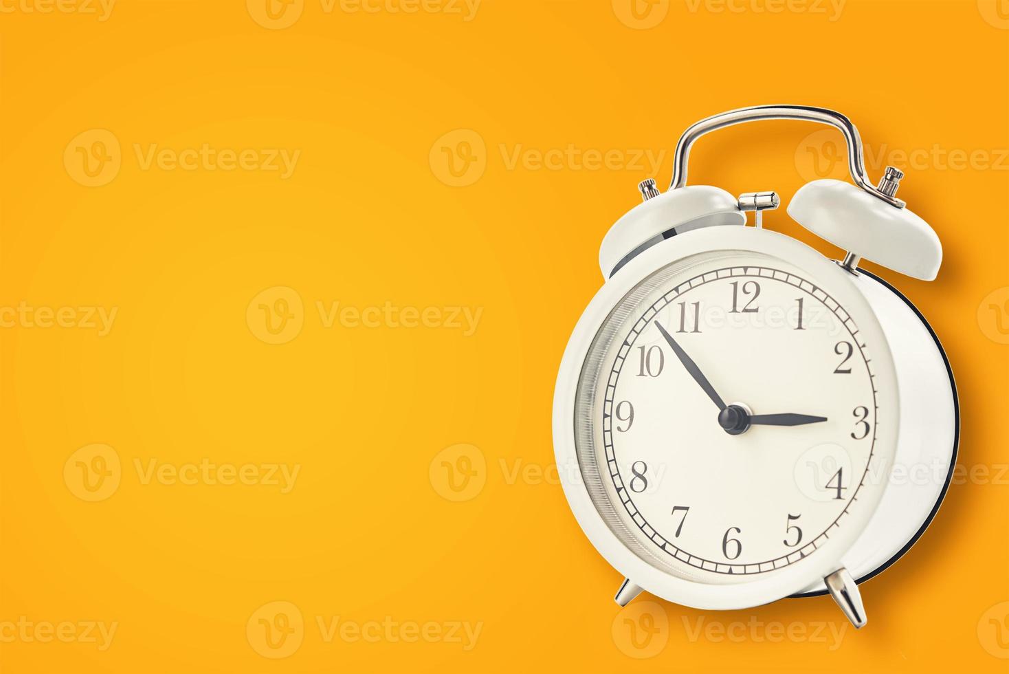 White vintage alarm clock on a yellow background photo