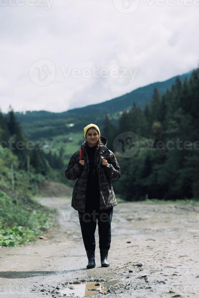 Active healthy female hipster model hiking along forest mountain road. photo