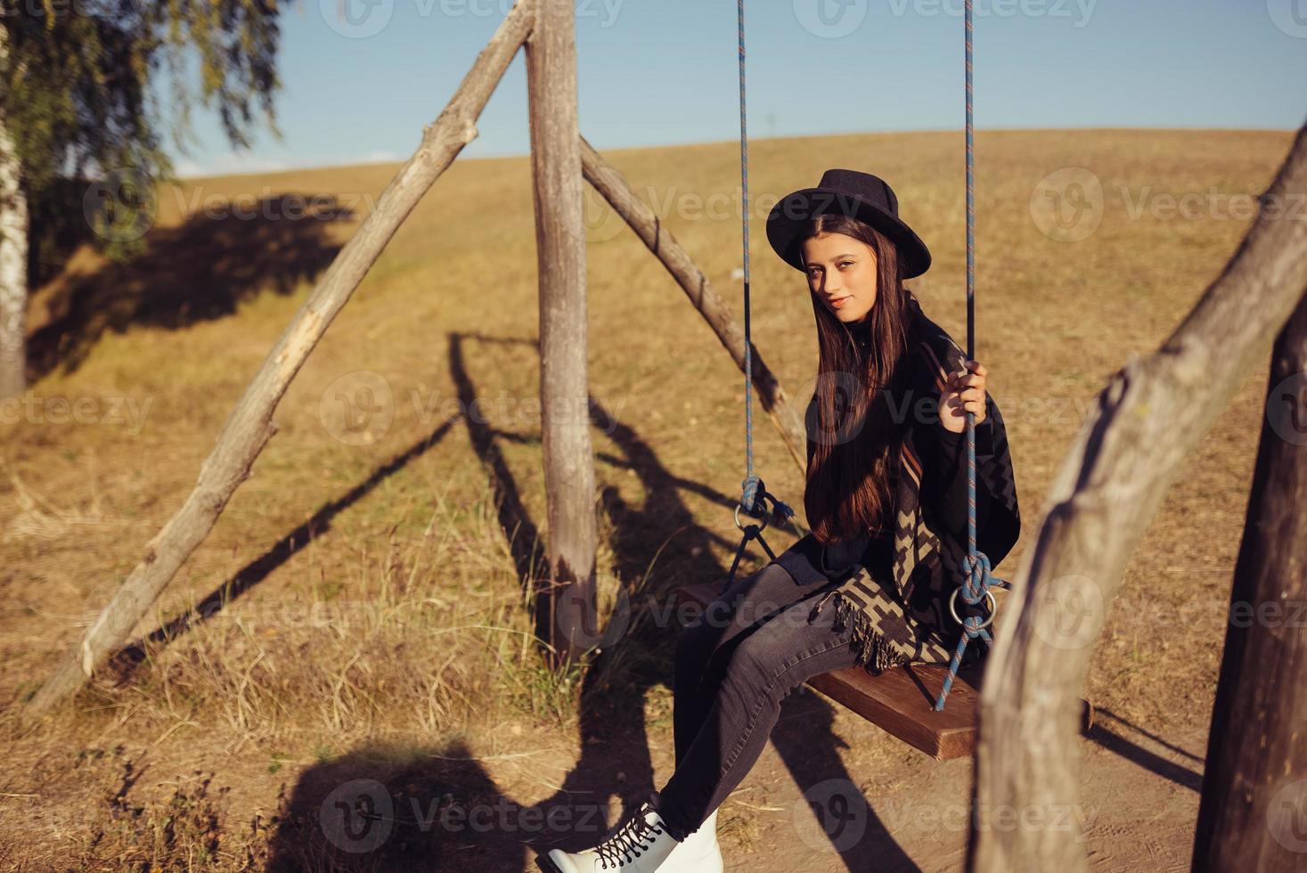 hermosa mujer joven paseos en un columpio en el campo foto