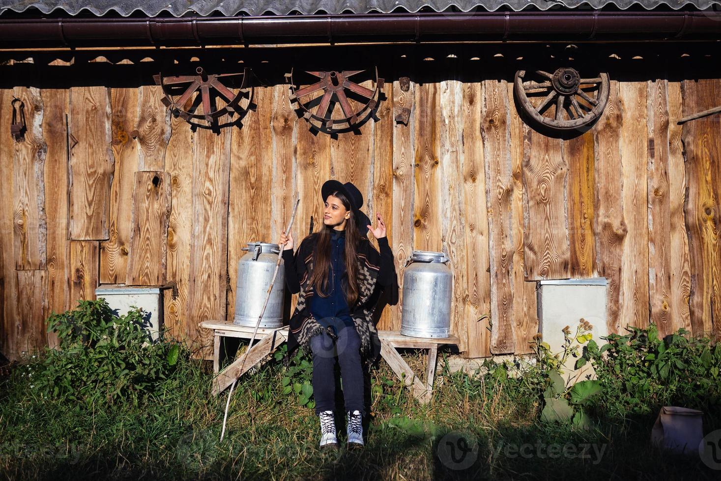 Woman sits on a bench with milk cans on a farm photo