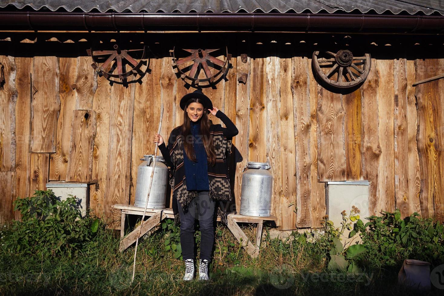 Woman sits on a bench with milk cans on a farm photo