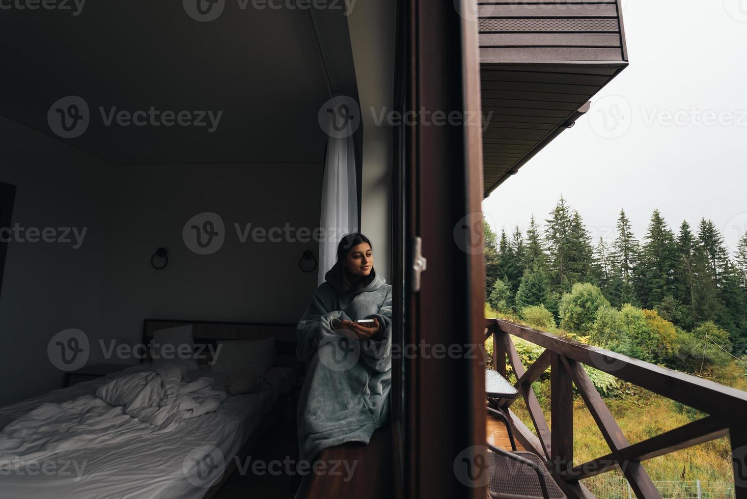 Woman sits on the windowsill and looks at the mountains photo