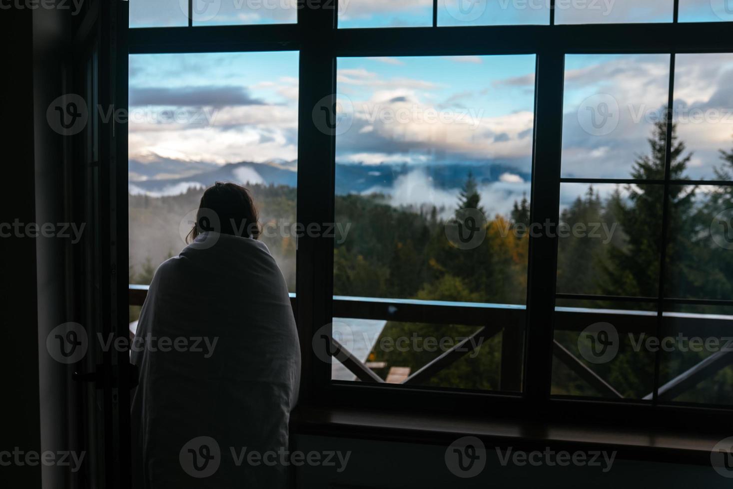 Young woman is looking through the window at the mountains photo