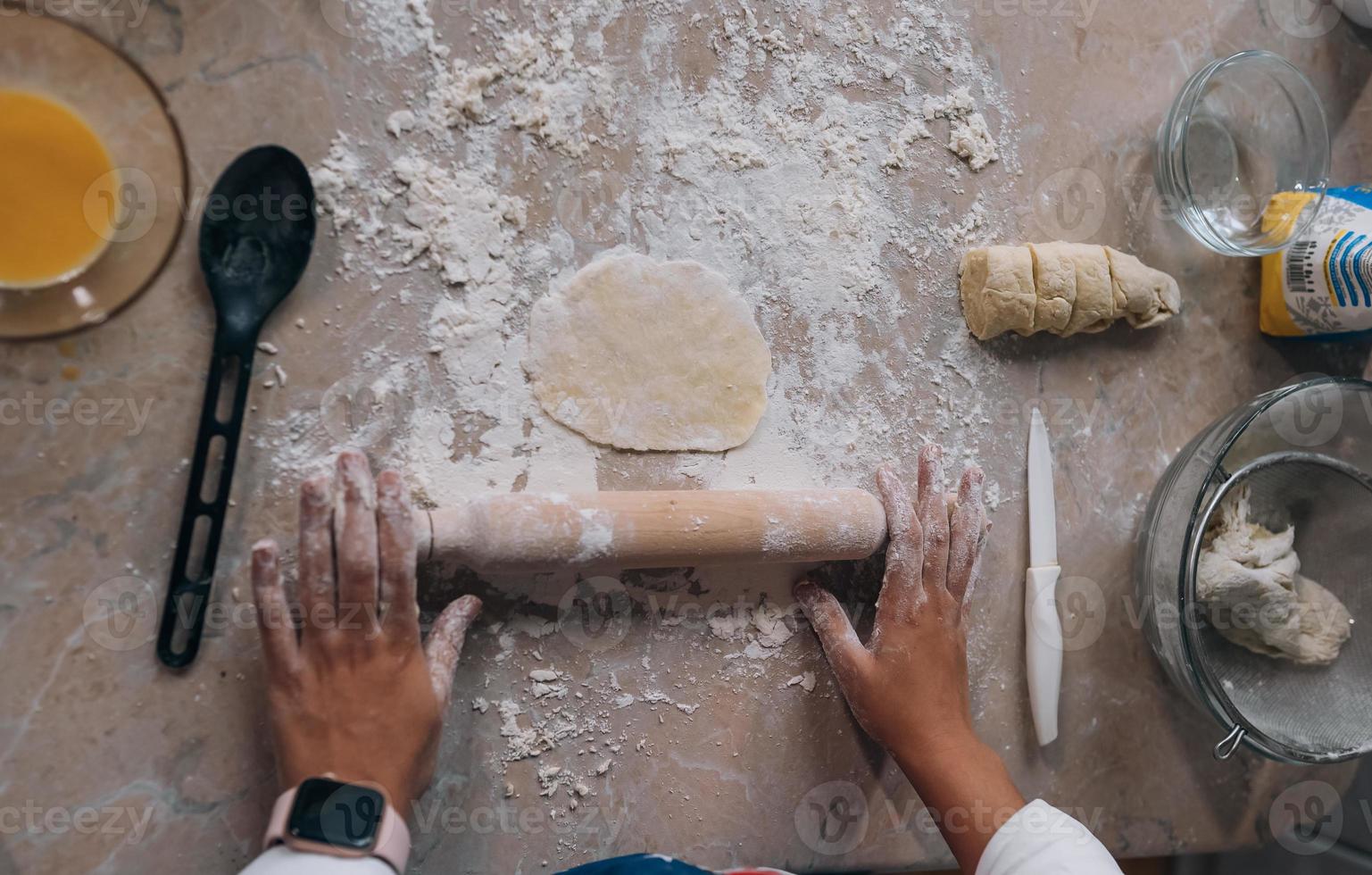 Close-up of young woman rolling dough with rolling pin photo