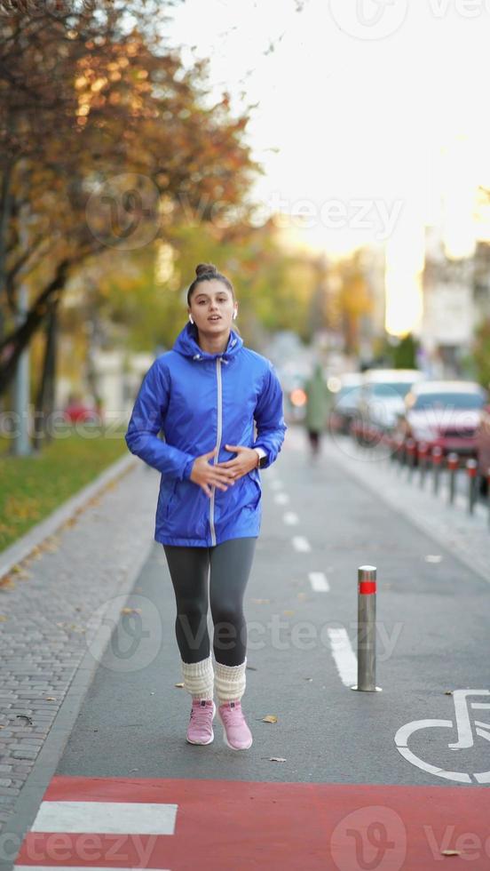 la vista frontal de una mujer hermosa está trotando al aire libre el día de otoño. foto