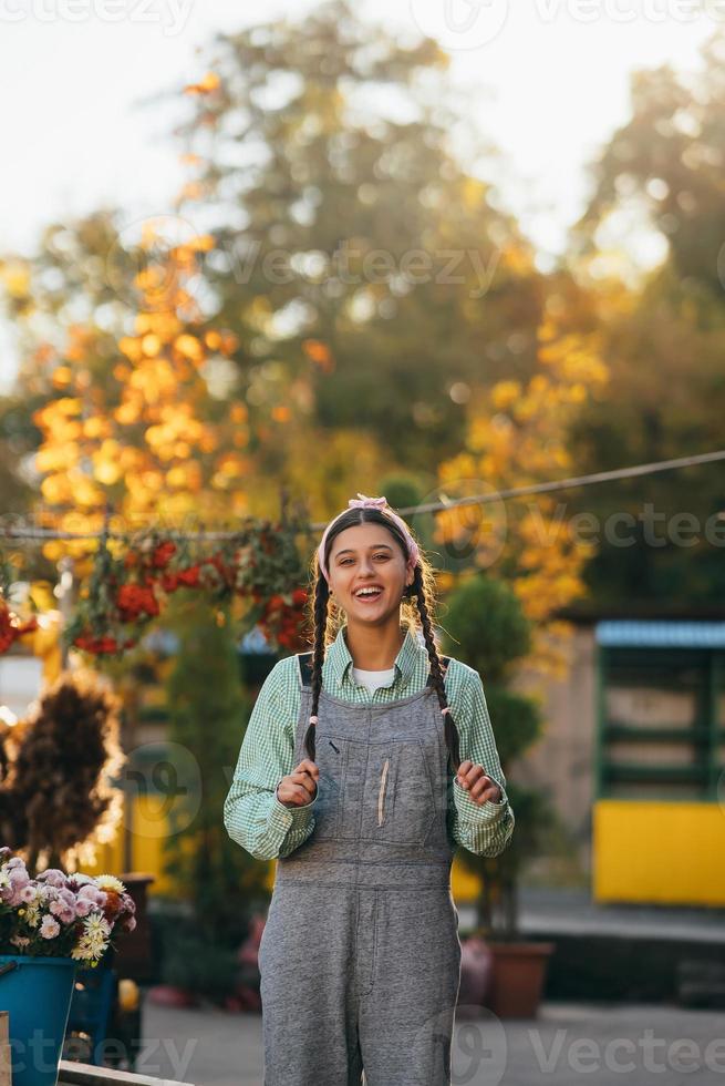 granjera juguetona con overoles de mezclilla sonriendo sinceramente mientras posa. foto