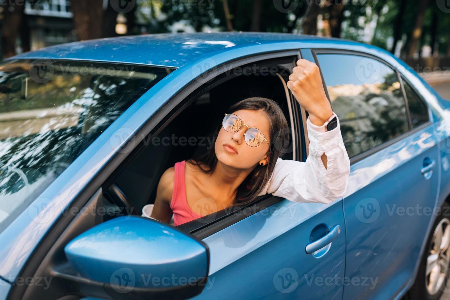 A young angry woman peeks out of the car window photo