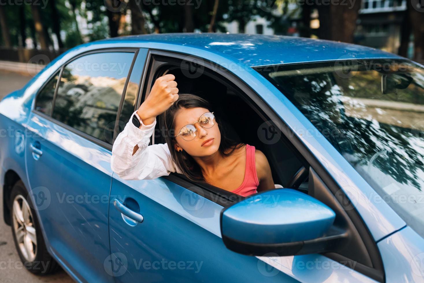 A young angry woman peeks out of the car window photo