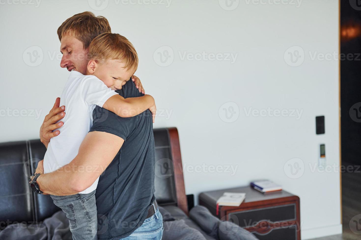 Embracing each other. Father and son is indoors at home together photo