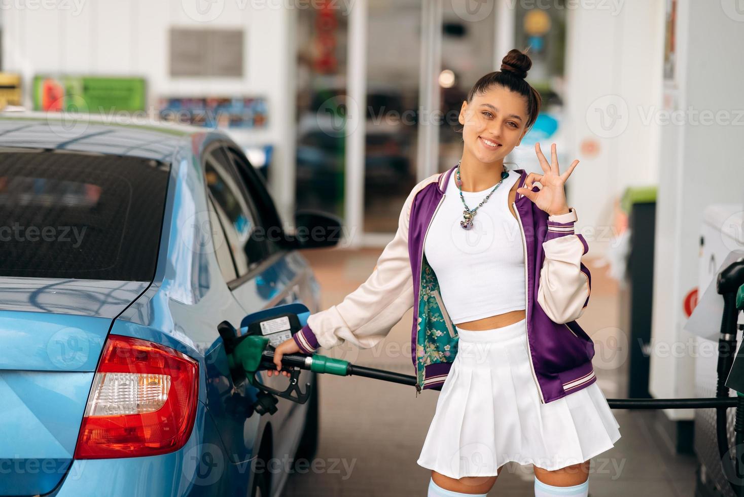 mujer llenando su auto con combustible en una gasolinera foto