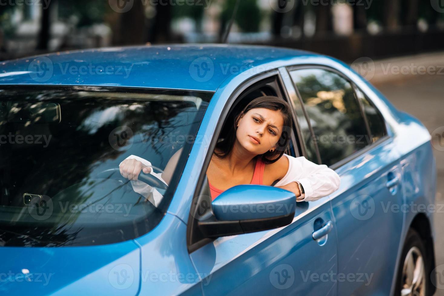 A young angry woman peeks out of the car window photo