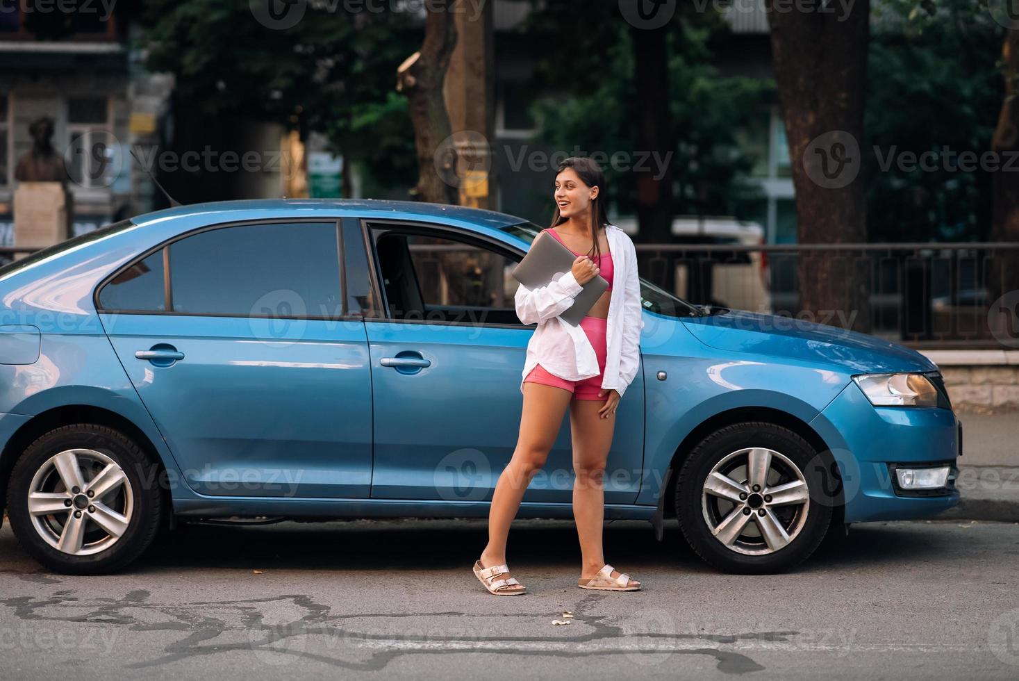 mujer joven caminando al aire libre sosteniendo una computadora portátil foto