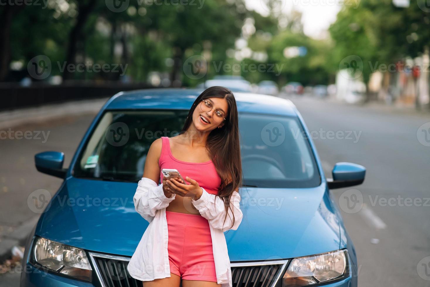 mujer usando teléfono móvil cerca del auto en la calle foto