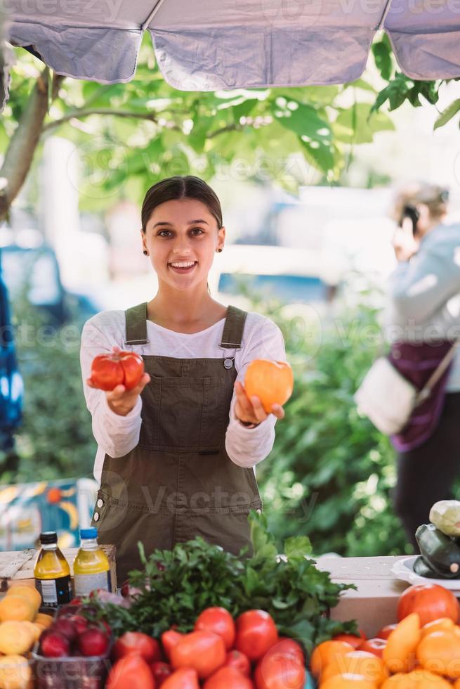 joven vendedora sosteniendo tomates de cosecha propia en las manos foto