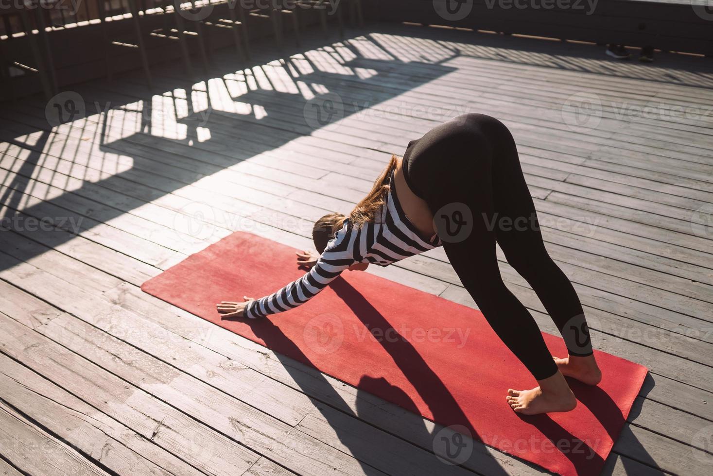 Woman doing yoga exercises on house roof in early morning photo