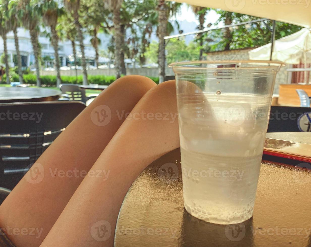 a cafe near the sea, plastic furniture stands near palm trees and a stage with equipment. rest of tourists, a man sits on a chair and drinks a cold drink from a plastic glass photo