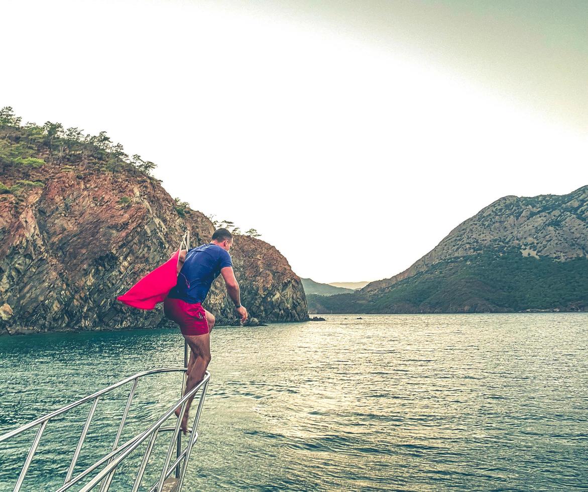 rest on the sea, a walk on a yacht on the waves. a man in a T-shirt and shorts dives into the water, underwater swimming. sunset walk on the water photo