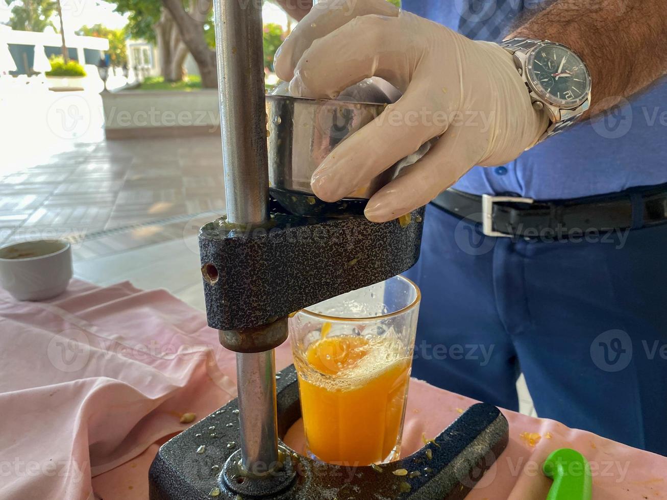 The process of making freshly squeezed yellow orange juice, a man squeezes juice into a glass with his hands in a hotel in a warm eastern tropical country southern paradise resort photo