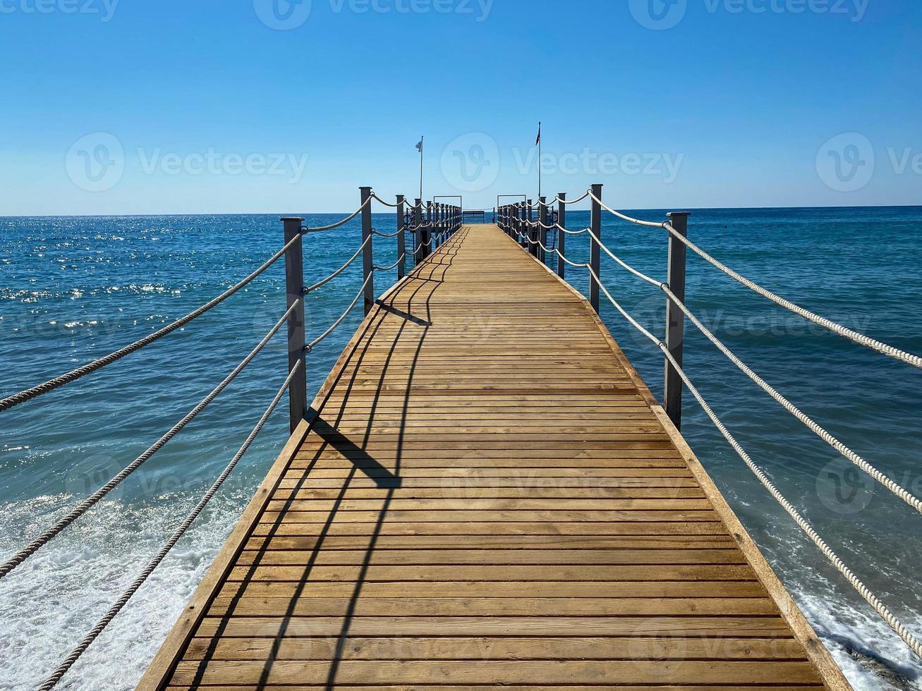 A wooden long pontoon, a pier with a rope railing on the sea on the beach on vacation in a paradise warm eastern tropical country resort photo