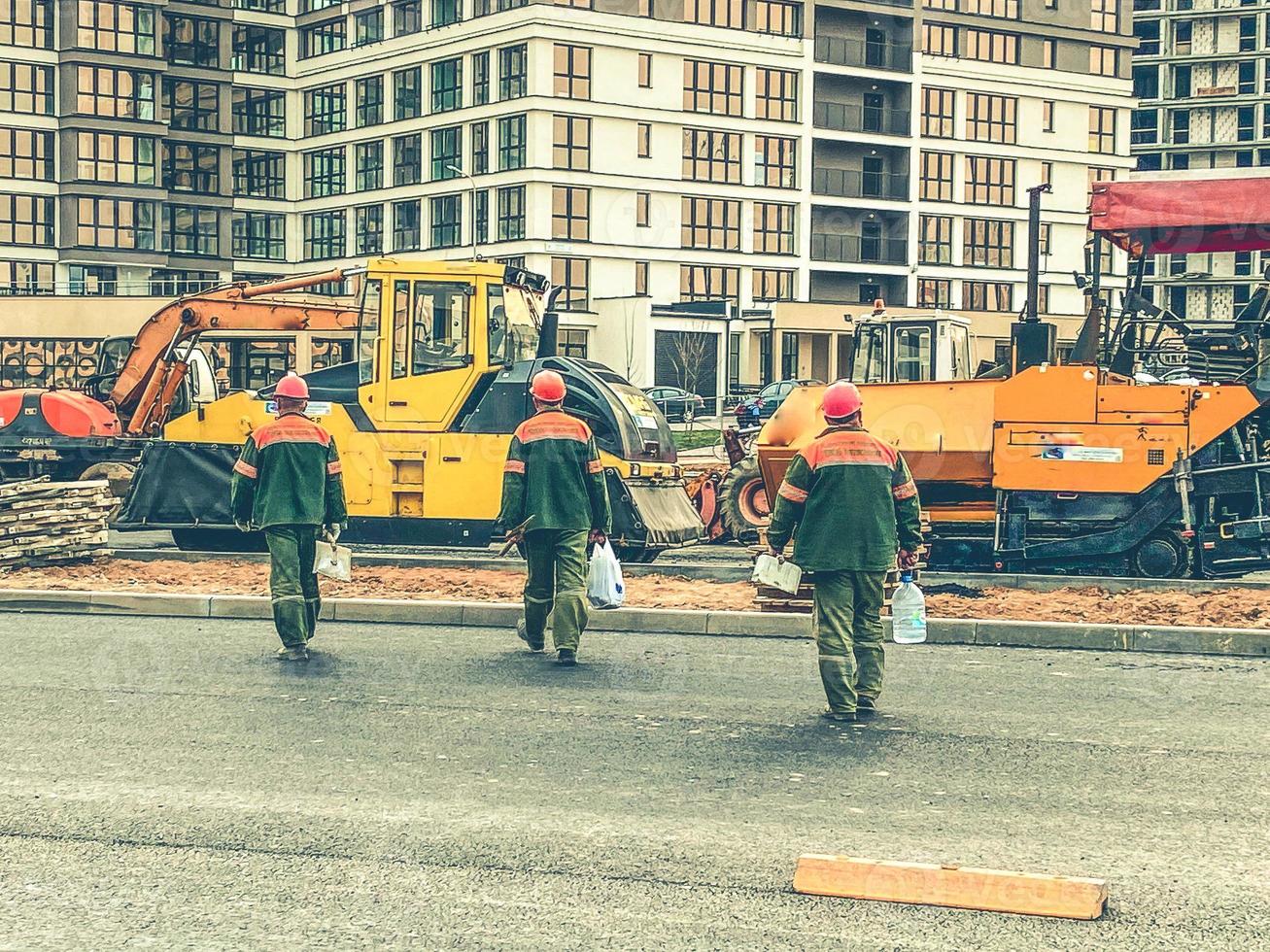 workers in orange helmets and protective uniforms are on the construction site. construction of a new microdistrict in the city center. protective clothing for workers photo