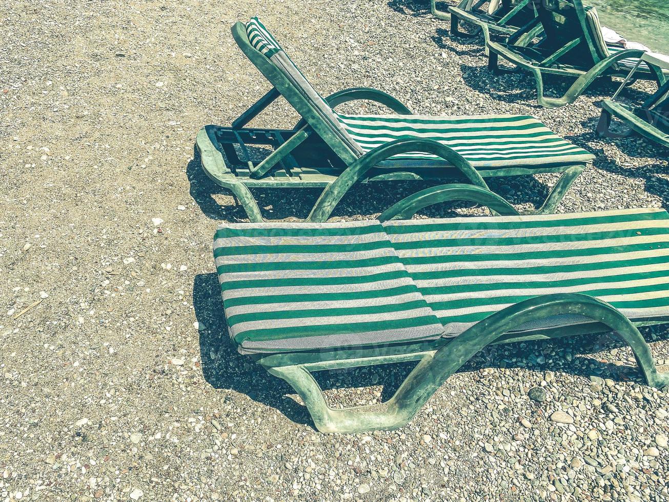 vacation by the sea on the beach. on the pebbly ground there are sun loungers for sunbathing tourists. on sunbeds mattresses and green fabric photo
