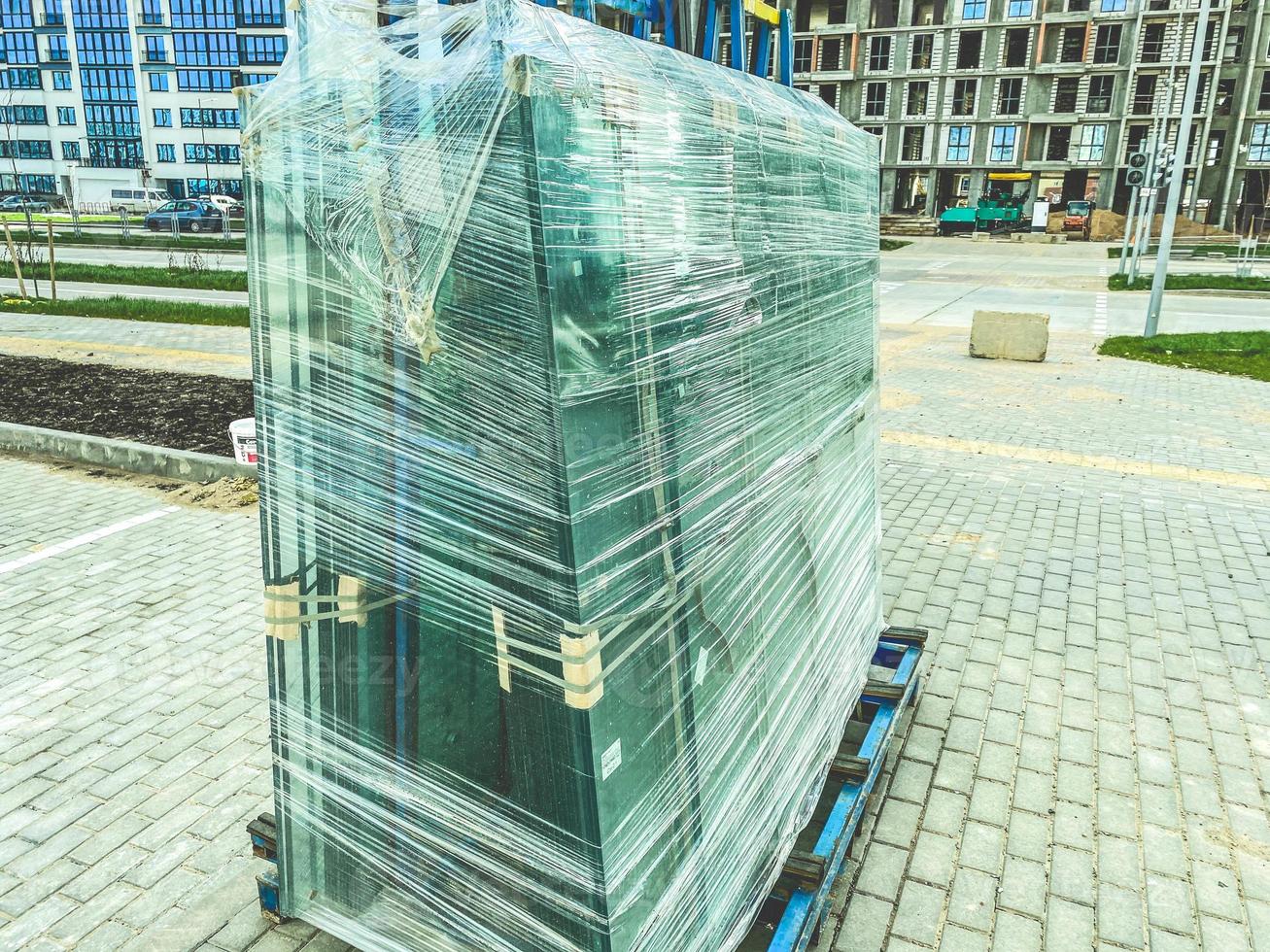 construction of a new microdistrict in the city center. building material lies at the construction site. glass windows with frame packed in film photo