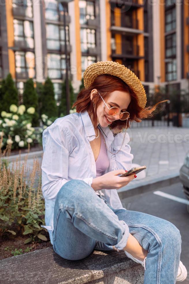 Young lady sitting stairs typing device outside urban city street photo