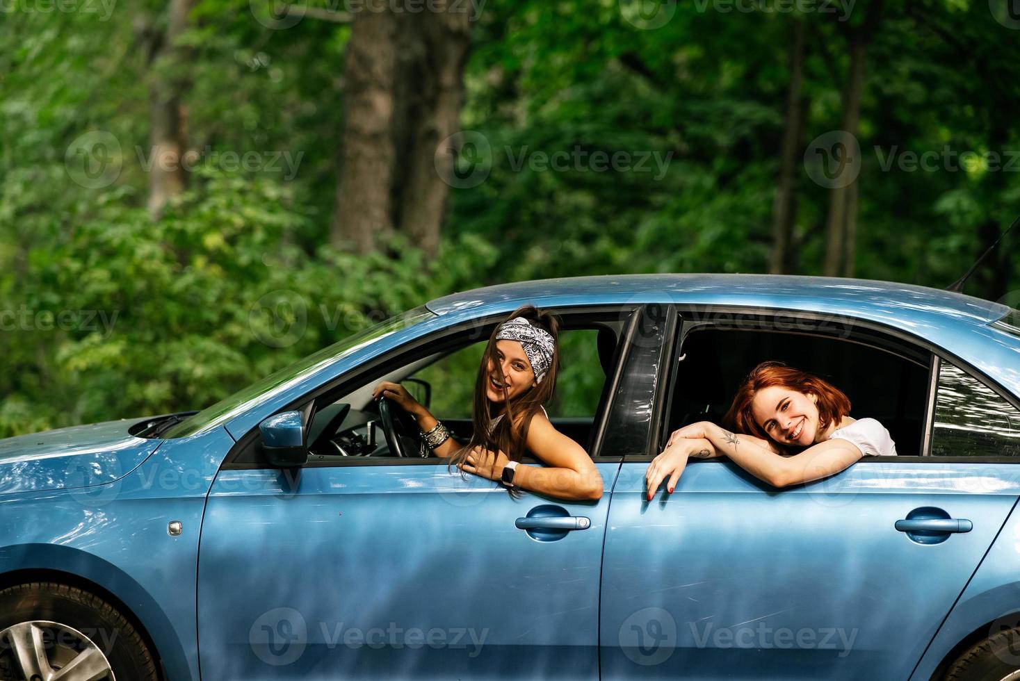 Two girlfriends fool around and laughing together in a car photo